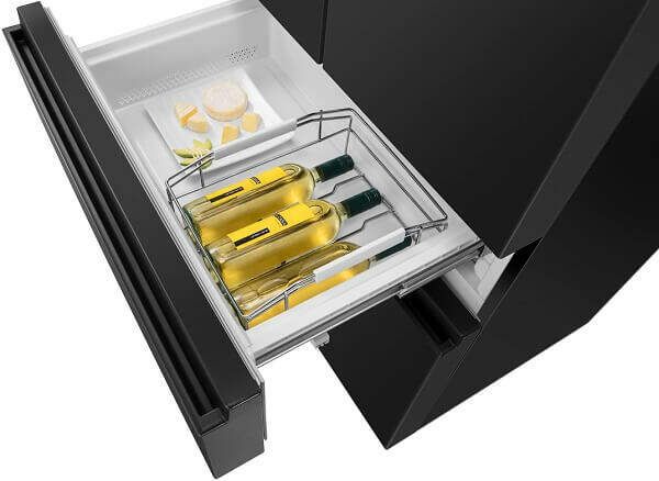 Hisense kõrgläikega musta värvi kõrvalkülmik, NoFrost süsteemiga, 480-liitrise mahutavusega, kõrgusega 182 cm. Seadmel on avatav külmiku sahtel koos kuldsete pakenditega.