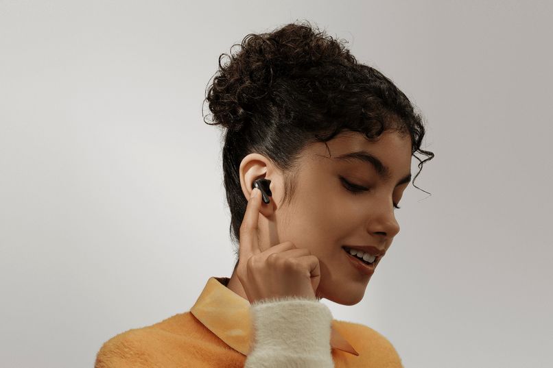 Naine kannab Xiaomi Redmi Buds 5 Pro juhtmevabasid kõrvaklappe, värvi midnight black. Kõrvaklapid on minimalistliku disainiga.